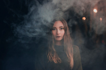 Portrait of a young woman in smoke in defocus. Place for text