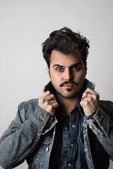 Vertical headshot of serious stylish man looks straight with confident expression, wears denim jacket, isolated.