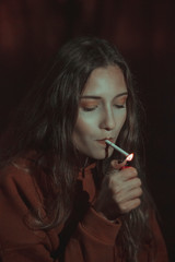 Fototapeta premium A beautiful girl lights a cigarette at night. Vintage photos 