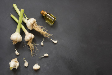 Glass bottle of garlic oil  and Ripe and fresh garlic plant on wooden or rustic table, alternative...