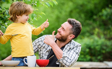 Menu for children. Homemade meal. Food habits. Little boy with dad eating food picnic yard nature background. Summer breakfast. Healthy food concept. Family weekend. Father son eat food and have fun