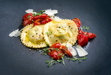 Traditionelle italienische Ravioli Pasta angeboten mit Parmesan Käse und gebratene Tomaten als...