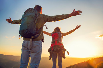 Couple with raised arms holding hands and looking at sunset