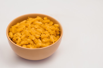 A small pile of gluten free corn pasta in plate on a white background. Gluten Free Pasta. Copy space