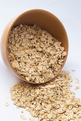 Oatmeal in a plate and scattered on a white background. Isolated on white background