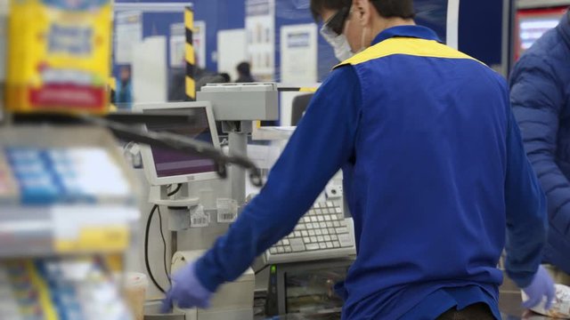 The seller in the mask at the cash register breaks and sells products.