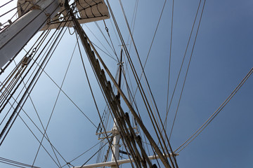 Naklejka premium Labyrinth of tall ship rigging lines and masts seen from below, against a deep blue sky, horizontal aspect