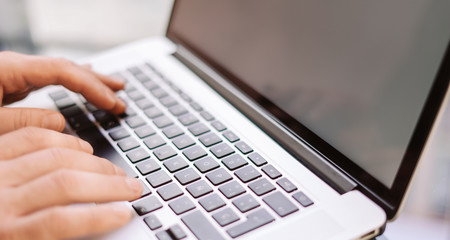 Close-up photo of male hands with laptop. Man is working remotely at home. Freelancer at work