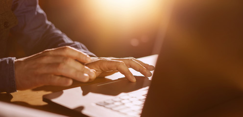 Close-up photo of male hands with laptop. Man is working remotely at home. Freelancer at work