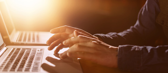 Close-up photo of male hands with laptop. Man is working remotely at home. Freelancer at work