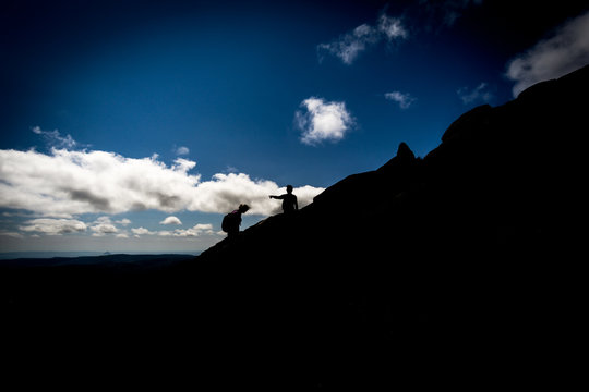 Silhouette Of Two People Climbing Mountain