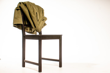 Jacket draped over wooden chair on white background
