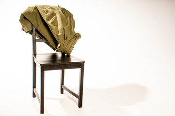 Jacket draped over wooden chair on white background