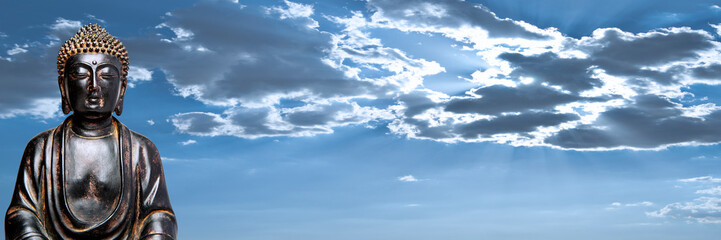A view of a replica statue of The Buddha with a dynamic, cloudy sky in the background
