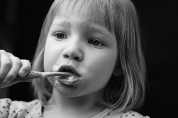 child is brushing his teeth. black and white portrait of a preschooler girl