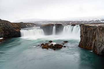 Famous godafoss waterfall in iceland in spring with snowy mountains