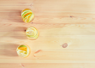 Glasses of white wine sangria with orange, green apple and lemon on wooden table.