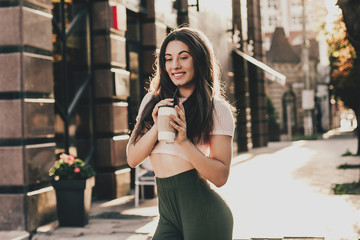 Beautiful smiling woman posing for the camera with coffee in the city.