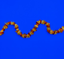 Amber beads on a blue background. Necklace, jewelry. Flat lay, copy space, top view.