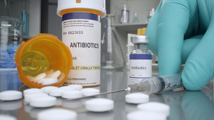 Antibiotic pills and vaccine vial in medical lab with syringe placed