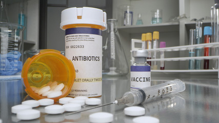 Antibiotic pills and vaccine vial in medical lab with syringe