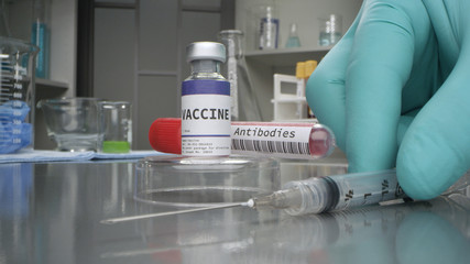 Vaccine and antibodies vial in medical lab with syringe placed