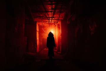 Creepy silhouette in the dark red illuminated abandoned building. Horror about maniac concept