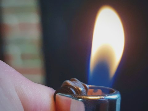 Cropped Image Of Hand Igniting Cigarette Lighter