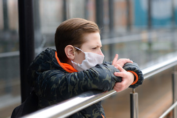 Portrait of sad caucasian child in face mask on closed playground outdoor. Coronavirus social distance quarantine.