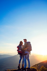Obraz premium Hikers with backpacks relaxing on top of a mountain and enjoying the view of valley