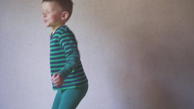 Happy fany boy child jumping on bed in bedroom. Childhood concept. skow motion.