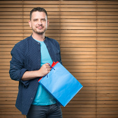 Young man wearing a blue outfit. Holding shopping bags.