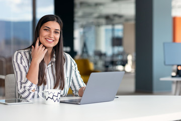 Smiling young business woman at work in modern office.