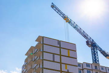 Construction crane on the construction of a residential building with a ventilated facade in the...