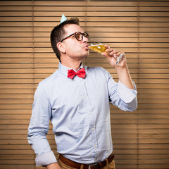 Man wearing a red bow tie and party hat. Drinking a champagne glass.