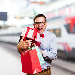 Man wearing a red bow tie and party hat. Holding gift. Looking happy.