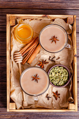 Glass cups of traditional Indian tea. Masala tea on a tray with ingredients.