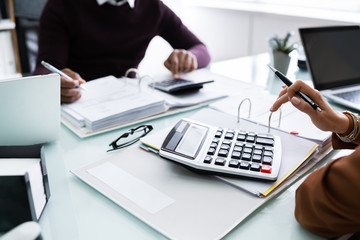 Two Businessman Using Calculator At Workplace