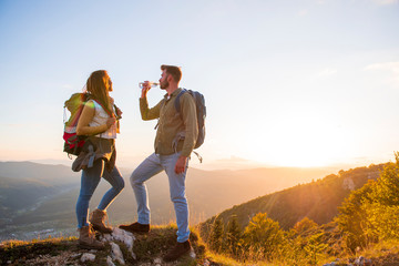 Young Couple Hiking On The Peak of Mountain drinking water