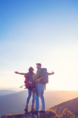 Hikers with backpacks relaxing on top of a mountain and enjoying the view of valley
