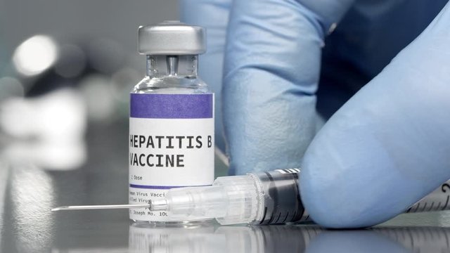 Hepatitis B vaccine vial in medical lab with syringe placed next to it.