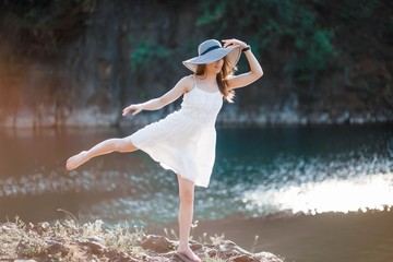 Girl gymnast at the sea. Young woman in white dress.
