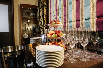 A three-tier modern dish with plates and a rod with a ring handle. Buffet table with plates and ice bucket for champagne