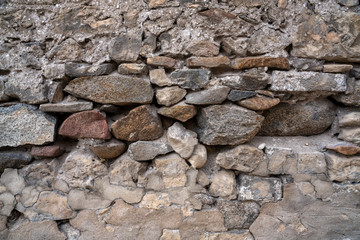 Stone Wall Texture Background with asymmetrical stones stacked together to form a vintage wall