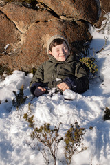 Fototapeta na wymiar Young boy exploring and playing on a snow covered Mount Wellington