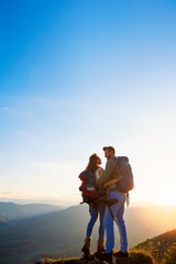 Obraz premium Hikers with backpacks relaxing on top of a mountain and enjoying the view of valley
