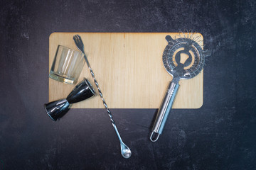 Bar food and beverage restaurant industry blank wooden sign with shot class liqueur measurer and mixed drink strainer and stirrer free of words and writing ready to add text 