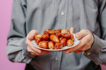 The guy holds in his hands dates (on a pink background). Ramadan