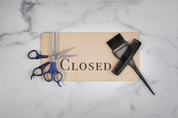 A closed wooden sign for hair salons and beauticians scissors and hair cutting shears applicators and black combs no people cosmetology industry 
