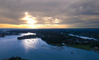 Panoramic drone aerial view over Sydney harbour on a cloudy sunset showing the nice colours of the harbour foreshore